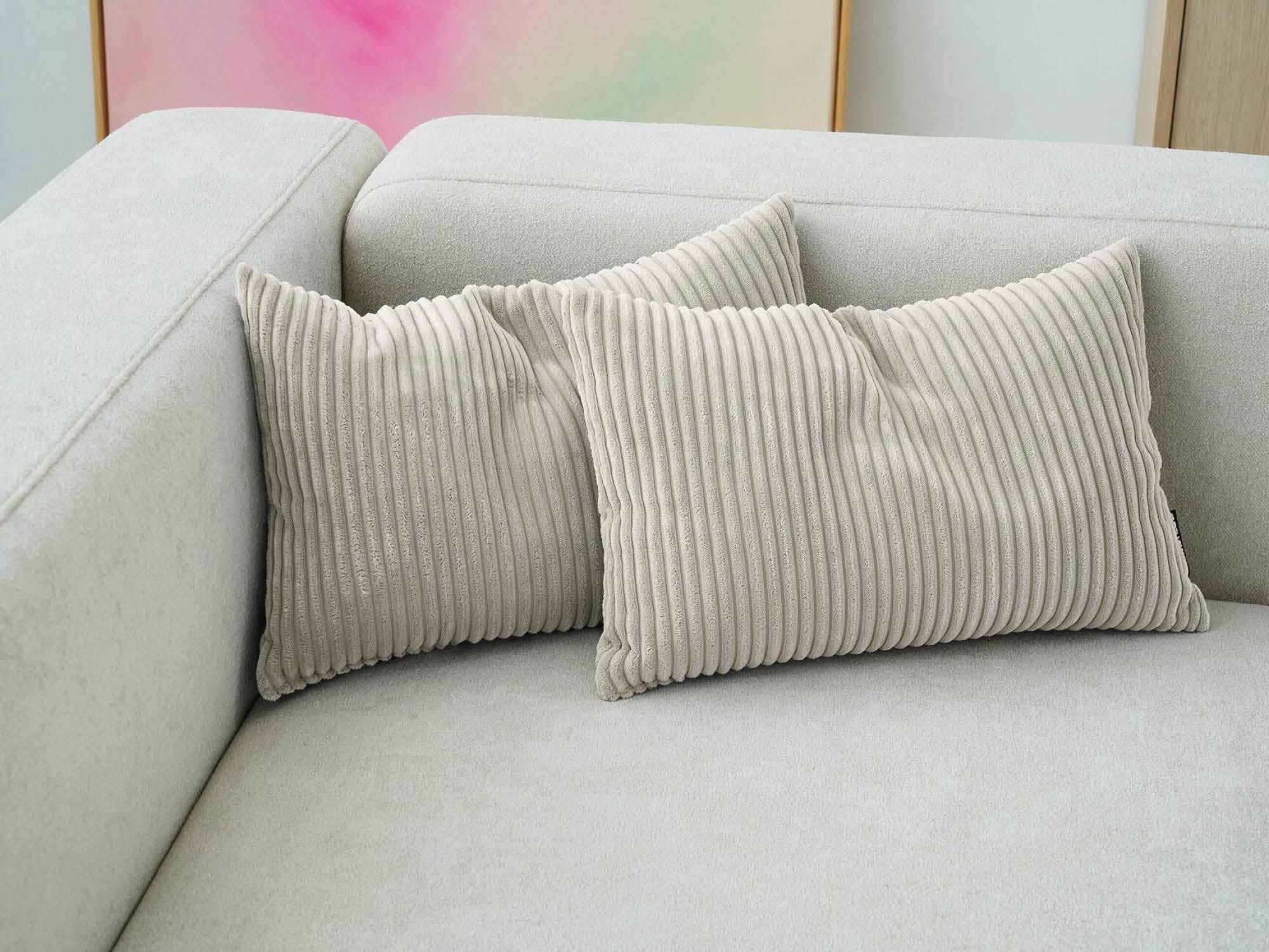zwei Cordkissen 'Rest' in beige auf einem beigen Sofa
